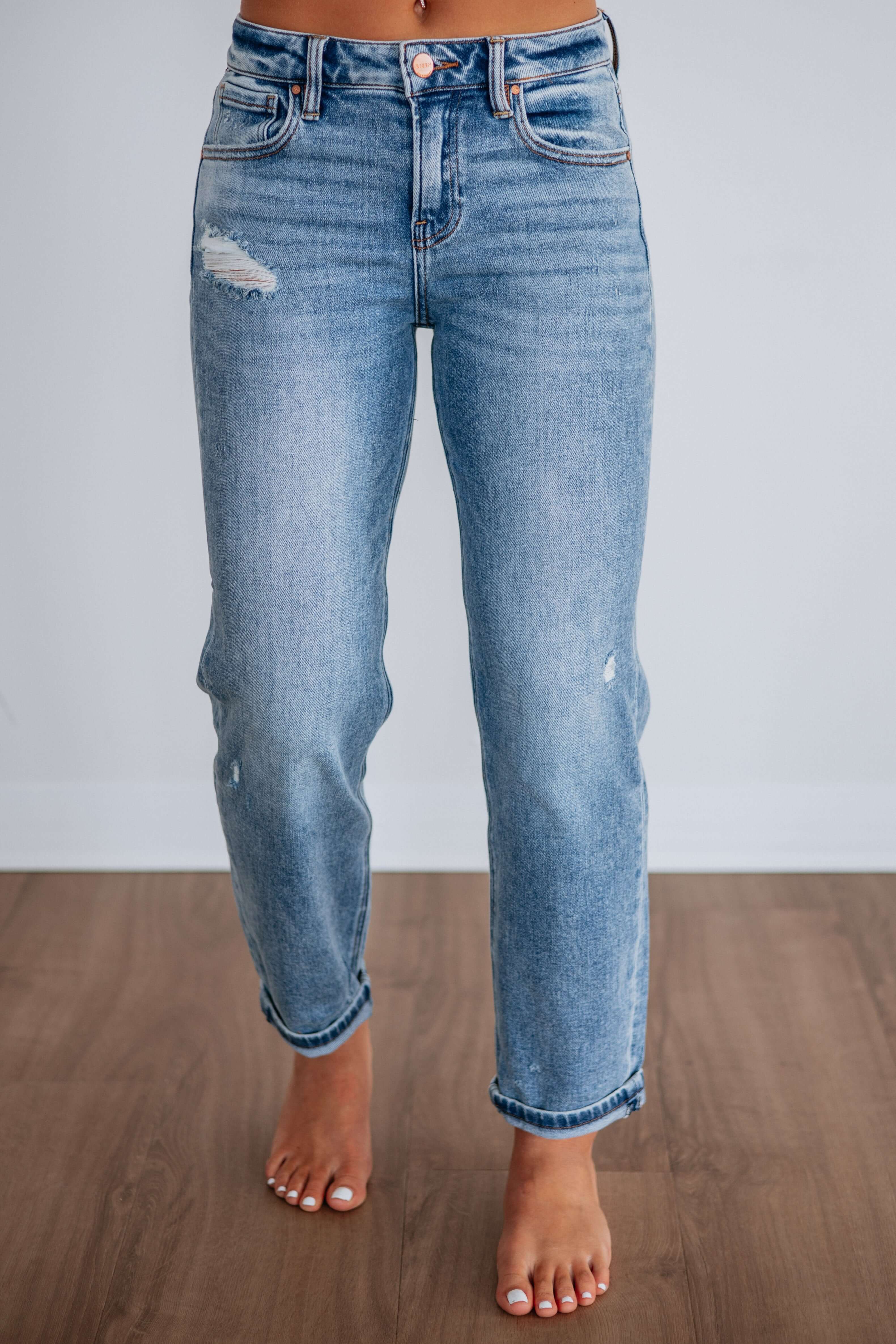 Woman wearing distressed Jeans showcased against a neutral background, highlighting a modern denim style.